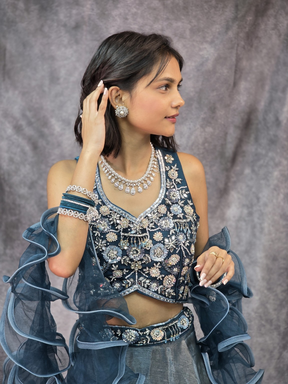 Woman wearing a teal embroidered Indian outfit with silver-tone necklace, earrings and bangles