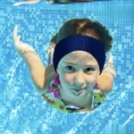 Child swimming underwater wearing a blue swimming headband
